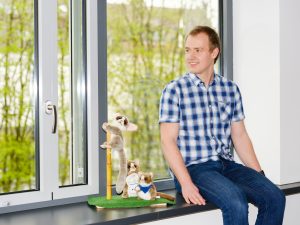 Athene Young Investigator Tobias Meuser sitzt zusammen mit Maki-Äffchen aus Plüsch auf einer Fensterbank. Sie sind das Maskottchen des Sonderforschungsbereichs MAKI - Multi-Mechanismen-Adaption für das künftige Internet.